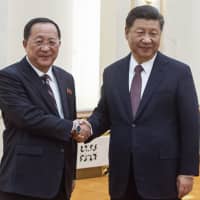 Chinese President Xi Jinping shakes hands with North Korean Foreign Minister Ri Yong Ho at the Great Hall of the People in Beijing on Friday. | POOL / VIA AP