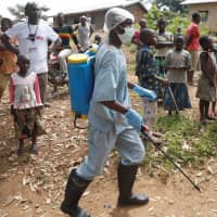 A health care worker sprays an area around the house of a man suspected to be infected with the Ebola virus, in Beni, North Kivu Province of Democratic Republic of Congo, Wednesday. | REUTERS