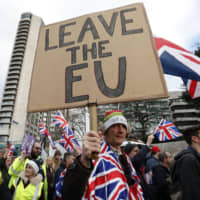 Protesters hold up placards and Union flags as they attend a pro-Brexit demonstration promoted by the United Kingdom Independence Party in central London on Dec. 9. | AFP-JIJI