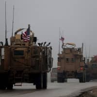 U.S. military vehicles drive through Syria\'s northern city of Manbij. Sunday. President Donald Trump announced last week that U.S. troops would depart from Syria, leaving Manbij residents dreading a long-threatened attack by Turkey. | AFP-JIJI