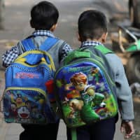Schoolchildren walk along a footpath in New Delhi on Nov. 27. | REUTERS