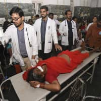 In this Dec. 14 photo, an Indian woman is brought for treatment after a case of suspected food poisoning, at a hospital in Mysore Karnataka state, India. Police on Saturday arrested three people after at least 10 died of suspected food poisoning following a ceremony to celebrate the construction of a new Hindu temple in southern India. | AP
