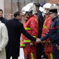 French President Emmanuel Macron shakes hands with a firefighter during a visit in the streets of Paris on Sunday, a day after clashes during a protest of Yellow vests (Gilets jaunes) against rising oil prices and living costs. | AFP-JIJI