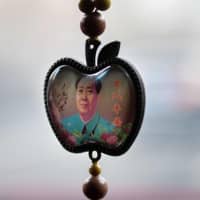 A portrait of late Chinese communist leader Mao Zedong hangs in a shaped apple pendant in Beijing. | AFP-JIJI