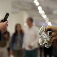 A man photographs a sculpture titled \"Made Off\" by artist Fredy Hadorn at the Art Miami show during Miami Art Week on Thursday. | AP
