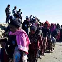 Myanmar Navy personnel escort Rohingya Muslims back to their camp in Sittwe, Rakhine state, on Friday. Nearly 100 Rohingya Muslims were forced back to Rakhine state after being detained at sea en route to Malaysia, police said on Nov. 28, stirring fears of a fresh refugee boat crisis. | AFP-JIJI