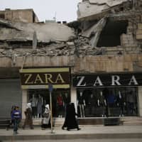 Women walk in front of clothing shops on a street in Manbij, north Syria, in March. On Friday, Syria\'s military announced it had taken control the flash-point Kurdish-held town. | AP