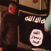 Army Sgt. 1st Class Ikaika Kang holds an Islamic State group flag after allegedly pledging allegiance to the group at a house in Honolulu last year. On Tuesday, Kang is scheduled to be sentenced for trying to help the Islamic State group. | FBI / U.S ATTORNEY\'S OFFICE, DISTRICT OF HAWAII / VIA AP