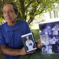 Clifford Kang, father of soldier Ikaika E. Kang, poses with photos of his son in Kailua, Hawaii, last year. Ikaika E. Kang, an active-duty U.S. soldier, arrested on terrorism charges that accuse him of pledging allegiance to the Islamic State group, is scheduled to be sentenced Tuesday. | BRUCE ASATO / HONOLULU STAR-ADVERTISER / VIA AP