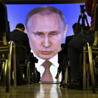 Journalists watch as Russian President Vladimir Putin gives his annual state of the nation address in Manezh in Moscow last March. | AP