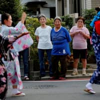 Residents watch folk dancers parade during a festival in the Sennari district of Sakura, Chiba Prefecture, in July. | REUTERS