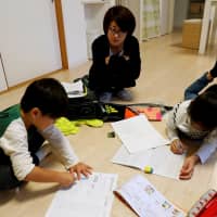 Motoko Hagiwara watches as her children do their homework in the living room of their house in the Higashinohara district in Inzai, Chiba Prefecture, on Nov. 6. | REUTERS