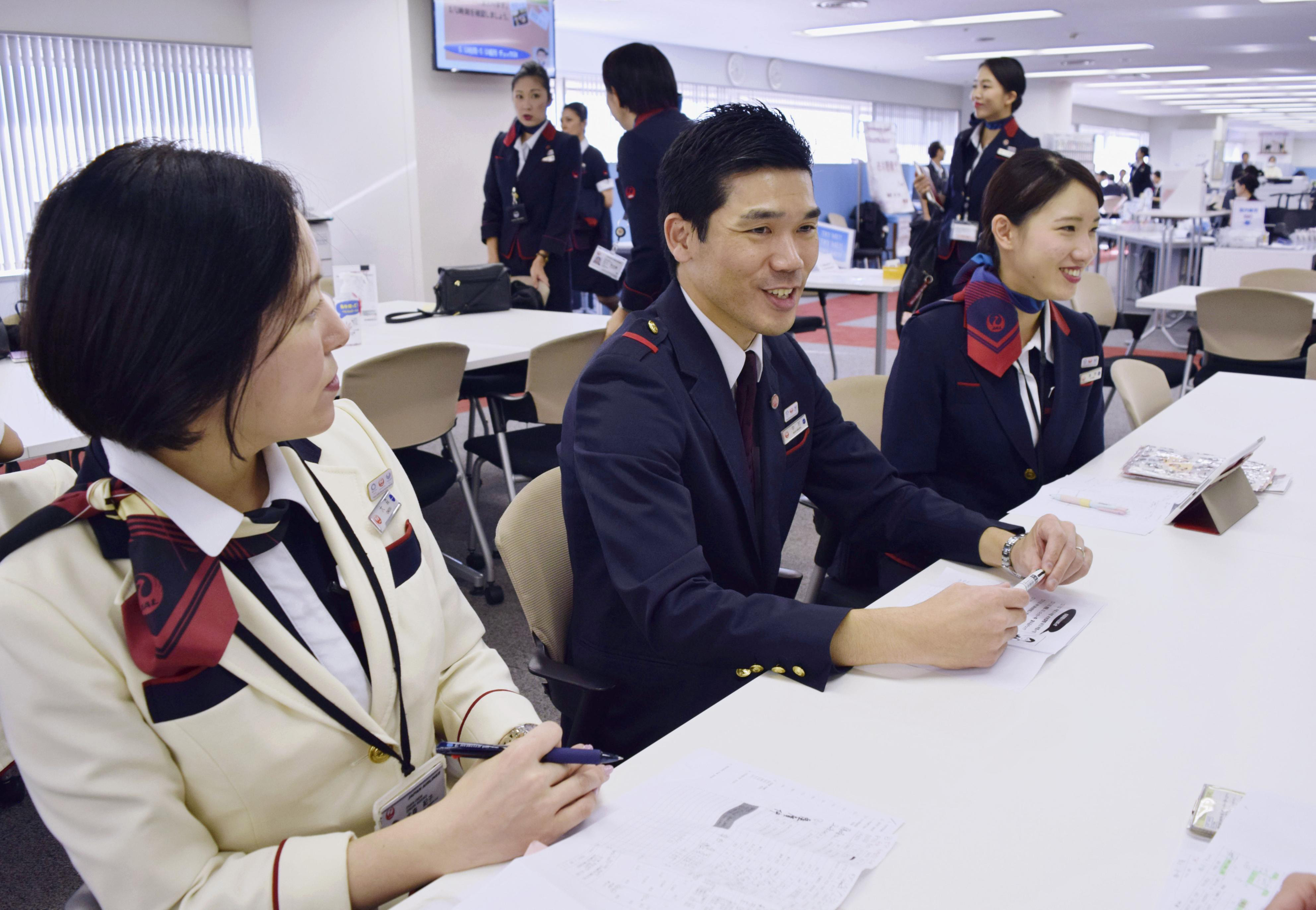 Japan Airline Co. flight attendant Hiroki Nakamura (center) talks with colleagues at a meeting in November at Tokyo’s Haneda airport. | KYODO