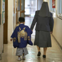 A nun takes the hand of a child donning a kimono for the traditional shichi-go-san festival at Seibi Home, a foster home in Kita Ward, Tokyo. | HIROTO HATA