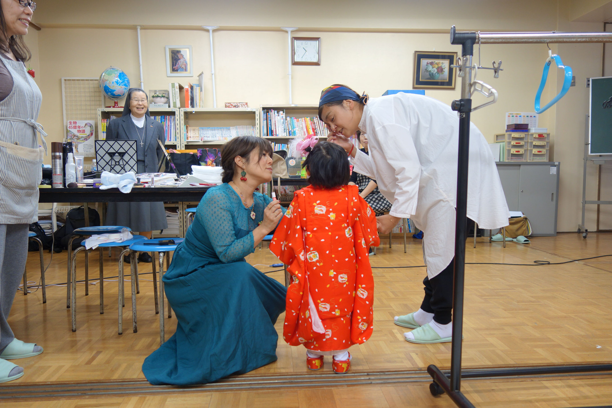 Volunteers from Ichigo Initiative apply makeup to a little girl who is preparing to take part in the shichi-go-san festival at Seibi Home in Tokyo. | ALEX MARTIN