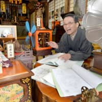Junno Nakamura, chief priest of Saihoji Temple in Kota, Aichi Prefecture, sits in a room with an antique record player and Edo-style mechanical dolls that he made. | CHUNICHI SHIMBUN
