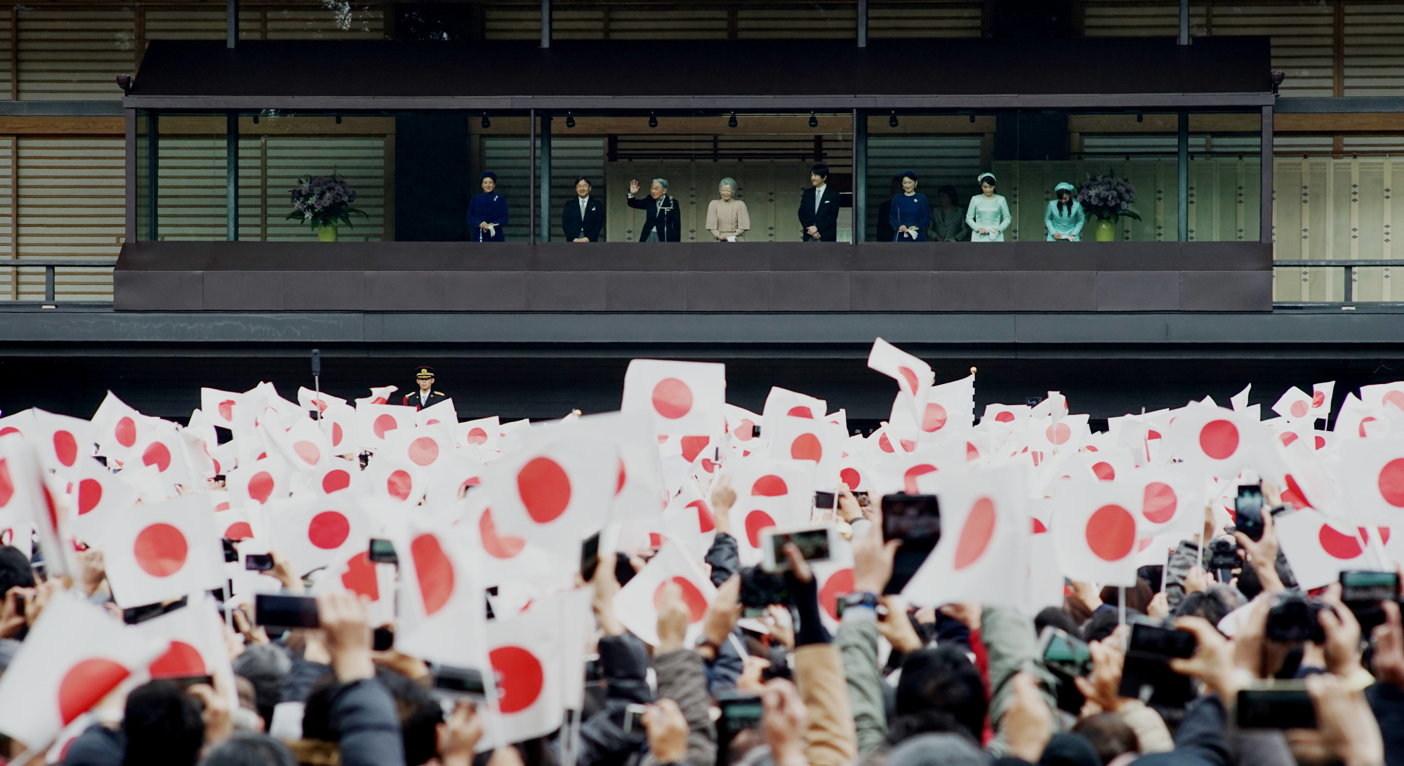 People wave Hinomaru flags as they celebrate Emperor Akihito