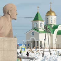 A bust of Soviet state founder Vladimir Lenin is seen in front of a Russian Orthodox church in Yuzhno-Kurilsk on the Island of Kunashiri, one of four islands known as the Southern Kurils in Russia but claimed by Japan, 2016. | REUTERS