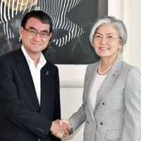 Foreign Minister Taro Kono (left) and his South Korean counterpart Kang Kyung-wha shake hands before talks on July 8 in Tokyo. | KYODO