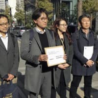 Lim Jae-sung, second from left, a lawyer representing South Korean plaintiffs in a World War II labor court case, holds a written request in front of the Nippon Steel &amp; Sumitomo Metal Corp. headquarters in Tokyo on Tuesday. | KYODO