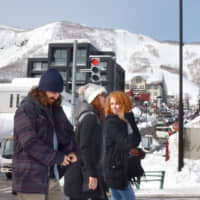 Tourists walk in Kutchan, Hokkaido, in February. | KYODO
