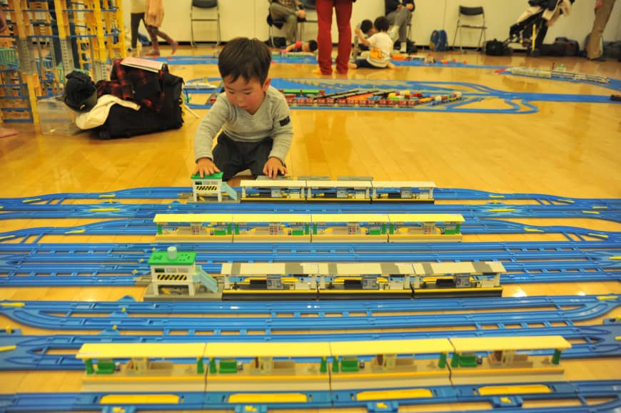 A child plays with battery-powered plastic trains on a giant track laid out at Purafesu, an event held at the Plaza North culture center in the city of Saitama on Saturday.