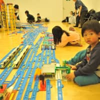 Children play with Plarail, a railway construction kit produced by toy-maker Takara Tomy, at Purafesu on Saturday. | ANDREW MCKIRDY