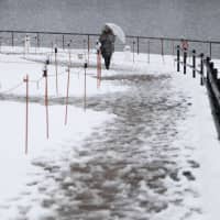A woman stands in the snow in the city of Toyama on Saturday. | KYODO