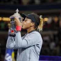 Naomi Osaka kisses the trophy after winning at the U.S. Open in New York in September. | KYODO