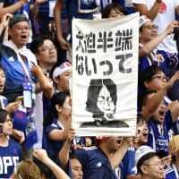 Soccer fans display a banner that reads \"Osako hanpa naitte,\" which translates loosely as \"Osako is way too good,\" as they cheer forward Yuya Osako during the World Cup in Russia this past summer. | KYODO