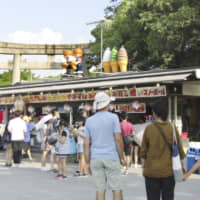 Tatsuko Utsunomiya\'s takoyaki (octopus dumpling) stand serves visitors at Osaka Castle Park in July. She was found guilty of tax evasion Wednesday. | KYODO