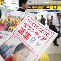 Leaflets to recruit volunteers for the 2020 Tokyo Olympics are handed out at Shinjuku Station in September. A resolution encouraging volunteerism that was co-sponsored by Japan was adopted Monday by the U.N. General Assembly. | KYODO
