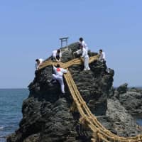 Hanging out: Teams of volunteers change the shimenawa  (sacred rope) of Meoto Iwa in Mie Prefecture. | STEPHEN MANSFIELD