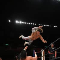 Wrestler Hiroshi Tanahashi dives on top of Jay White during a New Japan Pro-Wrestling event at Tokyo\'s Ryogoku Kokugikan in October. | COURTESY OF NEW JAPAN PRO-WRESTLING