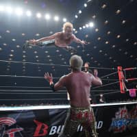 Kenny Omega dives on top of Kazuchika Okada during a New Japan Pro-Wrestling event in Osaka in June. | COURTESY OF NEW JAPAN PRO-WRESTLING