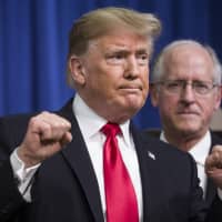 U.S. President Donald Trump raises his fists Thursday at the White House. He said Dec. 14 that China\'s decision to back off from new tariffs on cars and auto parts reflected the pain inflicted by the U.S. in their trade war. | BLOOMBERG