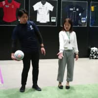 A 2019 Rugby World Cup official shows a prospective volunteer how to throw a rugby ball during an interview session in Tokyo on Monday. | RYUSEI TAKAHASHI