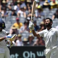 India batsman Cheteshwar Pujara (right) celebrates reaching a century with team captain Virat Kohli on Thursday during day two of the third test with Australia in Melbourne, Australia. | AFP-JIJI