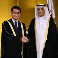 Qatari Ambassador Hassan Bin Mohammed Rafei Al-Emadi (right) shakes hands with Foreign Minister Taro Kono (left) during a reception to celebrate the anniversary of  Sheikh Jassim Bin Mohamed Bin Thani\'s accession to the throne at the Imperial Hotel on Dec. 13. | YOSHIAKI MIURA