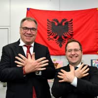 Albanian Ambassador Gjergj Teneqexhiu (left) welcomes Kosovan Ambassador Leon Malazogu (right) during a reception to celebrate Albanian flag day at the embassy in Tokyo on Nov. 30. | YOSHIAKI MIURA