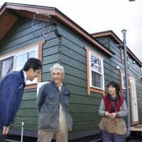 Quake evacuees Kazuyoshi Takeda (center) and his wife, Noriko, express gratitude to Shuichiro Oikawa, mayor of the town of Abira, Hokkaido, as they are given a temporary housing unit based on a trailer, on Wednesday in the town hit by the powerful quake in September. A total of 15 such housing units will be offered to affected households in Abira and the neighboring town of Atsuma. | KYODO