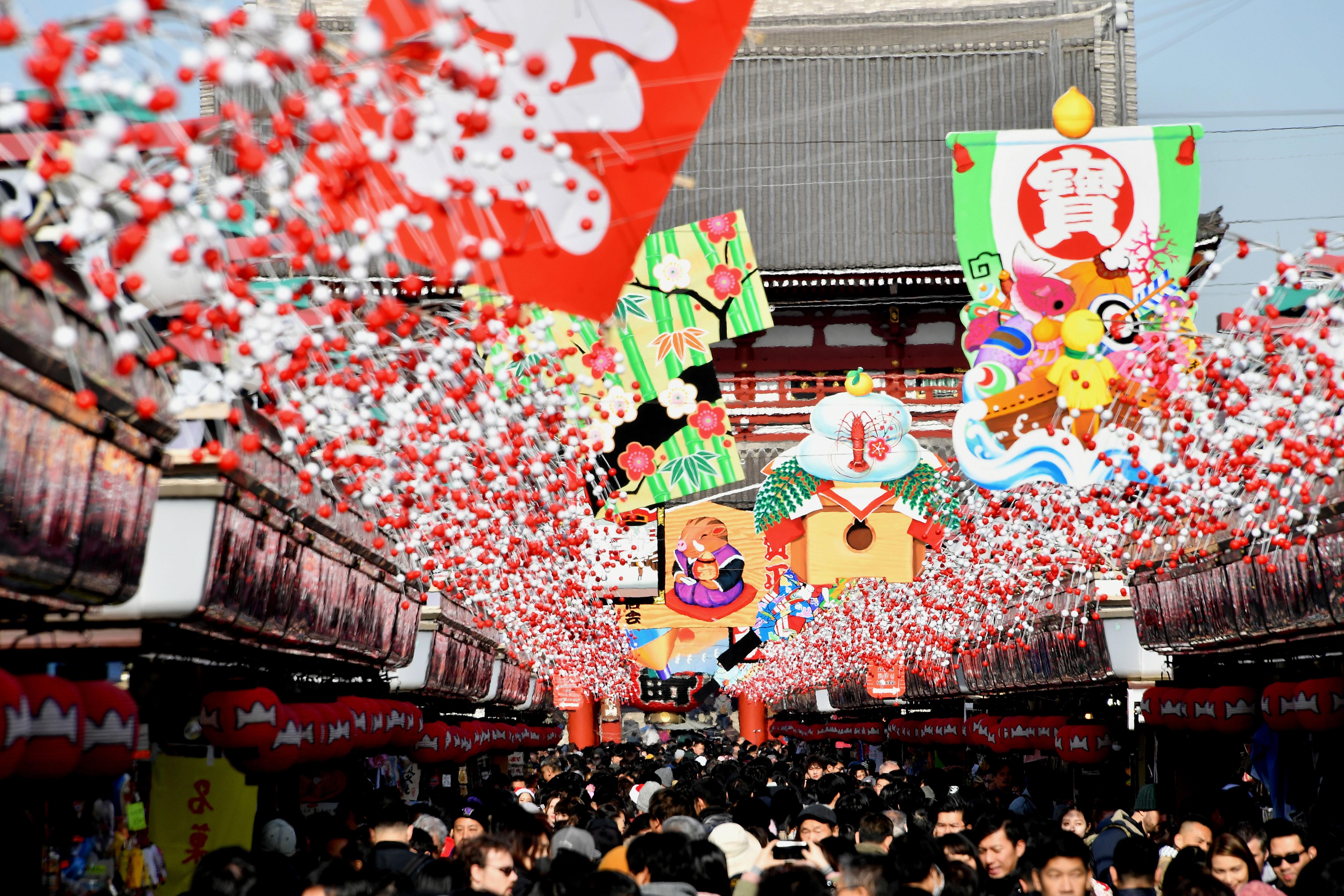 People fill the Nakamise-dori shopping strip leading to Sensoji temple in the Asakusa district of Tokyo on Tuesday, where a giant ema, a traditional Shinto plaque, with an illustration of wild boar &#8212; next year's Chinese zodiac sign &#8212; is displayed. | YOSHIAKI MIURA