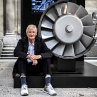 The founder of the Dyson company, designer James Dyson, poses next to the model of an engine during a photo session at a hotel in Paris in October. British electric appliance pioneer Dyson will switch headquarters to Singapore this year due to booming Asian demand but not because of Brexit, the company said Tuesday. | AFP-JIJI