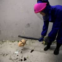 A female customer wearing protective gear smashes the head of a mannequin in an anger room in Beijing Saturday. | REUTERS