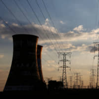 Electricity pylons are seen along the cooling tower of the defunct Orlando Power Station in Soweto, South Africa, in June 2018. | REUTERS