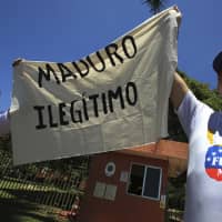 Venezuelan citizens living in Brazil hold a piece of cloth with a message that reads in Spanish \"Maduro illegitimate\" during a protest over the government of President Nicolas Maduro, outside the Venezuelan Embassy in Brasilia Wednesday, . | AP