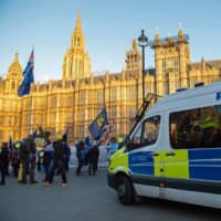 British police officers wait in their van as anti-Brexit activists demonstrate opposite the Houses of Parliament in London on Tuesday. | AFP-JIJI