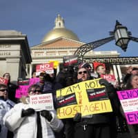 Internal Revenue Service employees Brian Lanouette (center right) and Mary Maldonado (right) join with others as they display placards during a rally by federal employees and supporters Thursday in front of the Statehouse in Boston, held to call for an end of the partial shutdown of the federal government. | AP