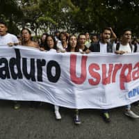 Students of Venezuela\'s Central University (UCV) in Caracas hold a banner reading \"Maduro usurper\" during a protest against the government of President Nicolas Maduro, called by opposition leader and self-proclaimed \"acting president\" Juan Guaido, on Wednesday. | AFP-JIJI