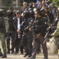 Damaso Lopez, a leader in Mexico\'s Sinaloa drug cartel, is escorted by police after his capture at an upscale apartment building in Mexico City in 2017. Lopez testified Wednesday at the U.S. trial of the Mexican drug lord known as El Chapo, implicating the kingpin\'s wife in his 2015 prison escape. | AP